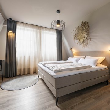 Jobs im Hotel Restaurant Seeblick in Gronau Modernes Schlafzimmer mit Doppelbett, Gardinen und minimaler Dekoration