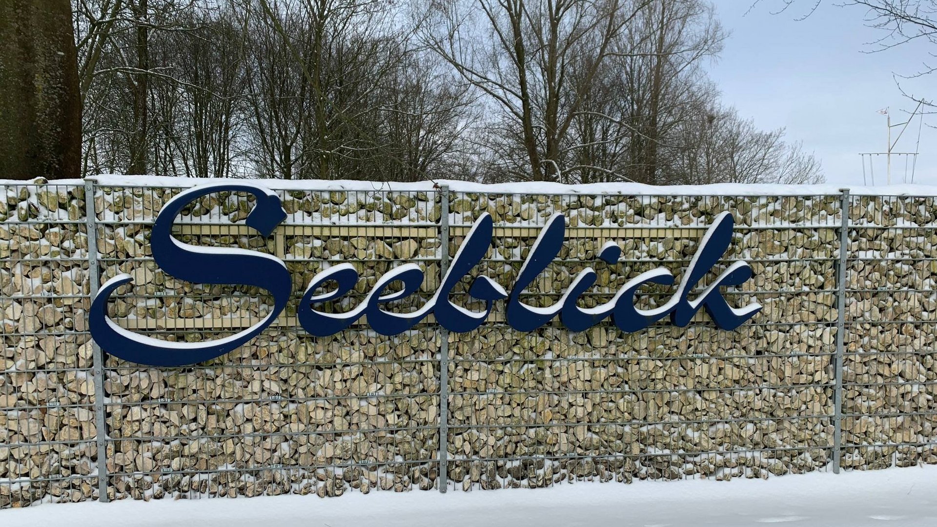 Hiking in North Rhine-Westphalia at any time of year Metal sign with the word Seeblick on gabion wall covered with snow