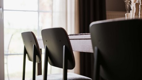 Appartementhotel Seeblick: Bildergalerie Dunkle Stühle an einem Holztisch vor hellem Fenster im Esszimmer