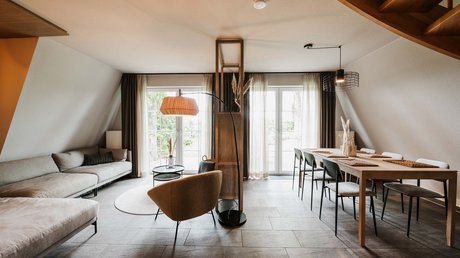 Appartementhotel Seeblick: Bildergalerie Helles Wohnzimmer mit Esstisch, Sofa und Sessel unter Dachschräge