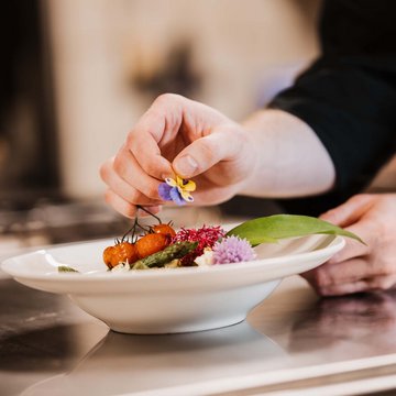 Jobs im Hotel Restaurant Seeblick in Gronau Koch dekoriert Teller mit essbarer Blume und Gemüse