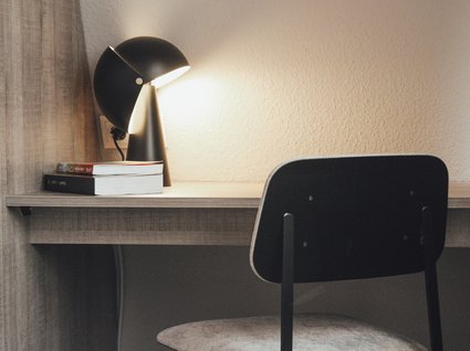 Seeblick: Ferienwohnungen Gronau Schreibtisch mit Lampe, zwei Büchern und einem Stuhl in einem einfachen Raum