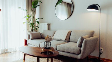 Appartementhotel Seeblick: Bildergalerie Gemütliches Wohnzimmer mit grauem Sofa, runder Vase und Stehlampe