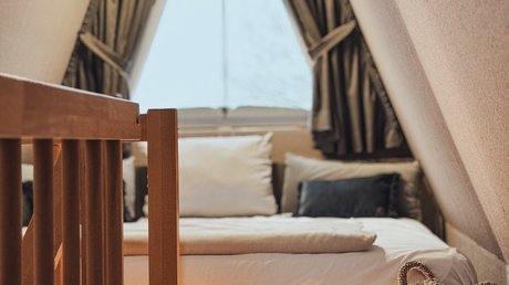 Appartementhotel Seeblick: Bildergalerie Gemütliches Schlafzimmer in einem Dachboden mit Dreieckfenster und Holzmöbeln