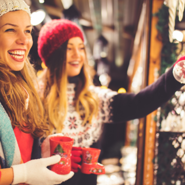 Hotel Seeblick in Gronau: Weihnachtsmarkt am Dreiländersee Zwei lachende Frauen mit Winterkleidung trinken Glühwein auf Weihnachtsmarkt