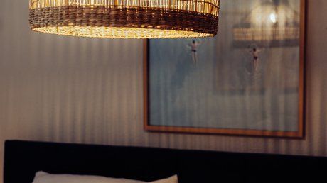 Appartementhotel Seeblick: Bildergalerie Geweven hanglamp boven een bed met witte kussens en ingelijste kunst