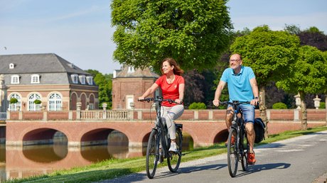 Appartementhotel Seeblick: Bildergalerie Een stel fietst bij zonnig weer langs een kasteel en een park