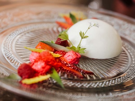 Restaurant Gronau: Seeblick Elegantes Dessert mit weißer Creme und roten Früchten auf Glasplatte