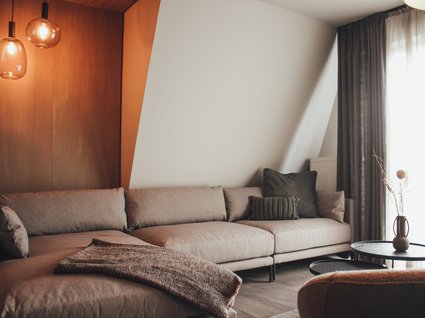 Seeblick: Ferienwohnungen Gronau Gemütliches Wohnzimmer mit grauem Sofa, Beistelltischen und dekorativer Vase