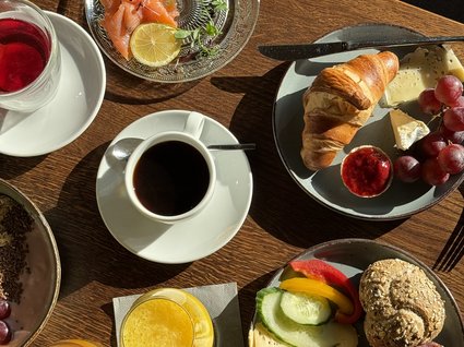 Holidays in an apartment with a lake view Breakfast table with coffee, croissant, cheese, cold cuts, and fruit juices