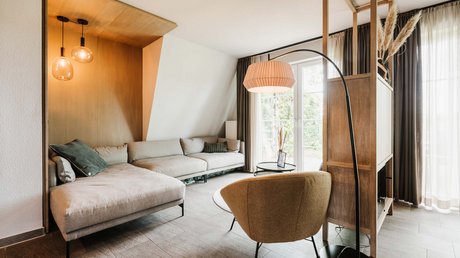 Appartementhotel Seeblick: Bildergalerie Modernes Wohnzimmer mit Ecksofa, Sessel und großem Fenster