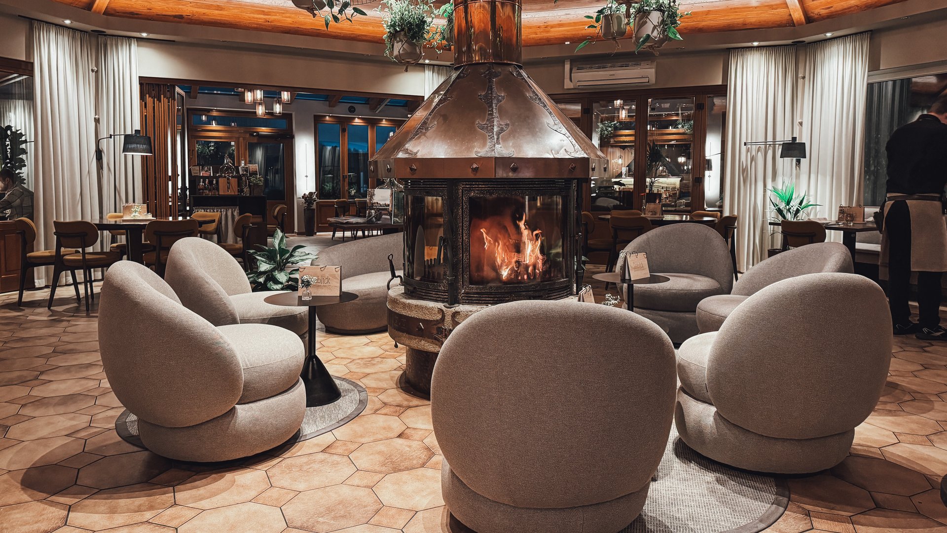 Restaurant Seeblick: Speisekarte Gemütliche runde Sitze um einen modernen Kamin in einem eleganten Innenraum