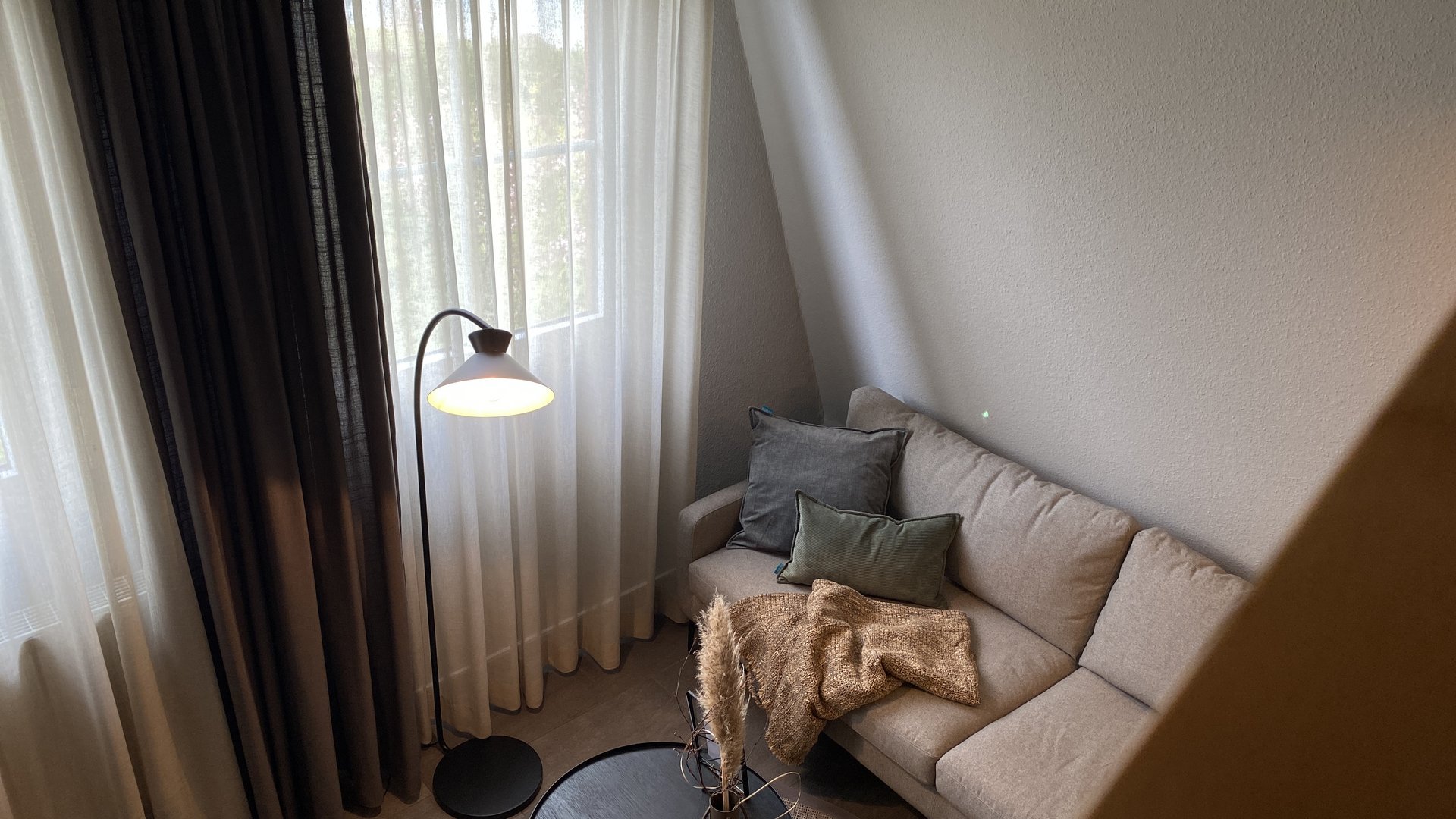 Seeblick: Ferienwohnungen Gronau Gemütliches Wohnzimmer mit Sofa, Stehlampe und Kaffeetisch mit Dekoration