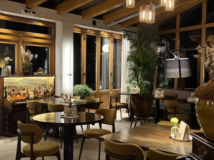Restaurant Gronau: Seeblick Cozy restaurant interior with wooden tables, yellow chairs, and a bar with spirits