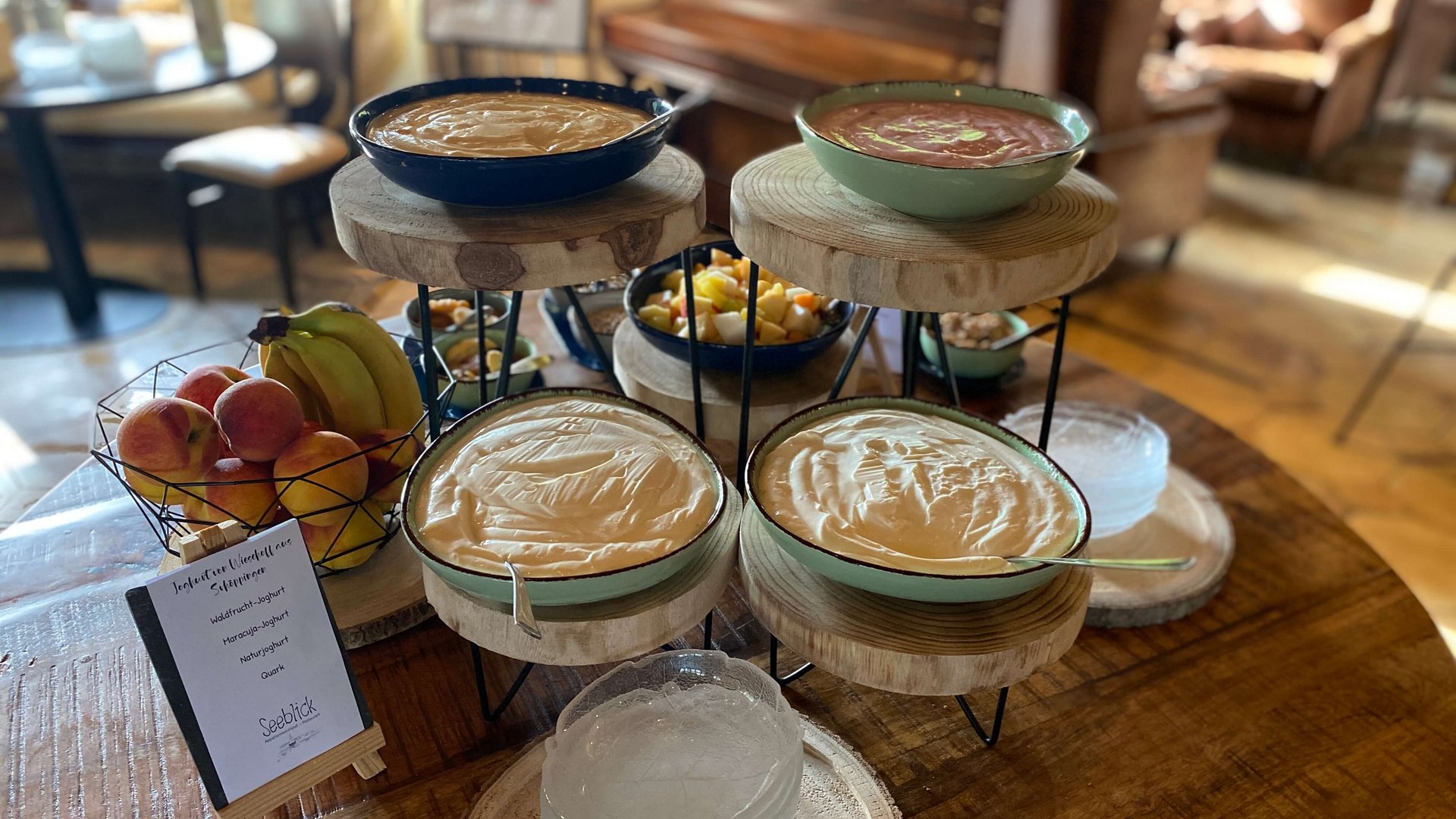 Breakfast at our restaurant Seeblick in Gronau Yogurt and fresh fruit on wooden trays in a cozy room