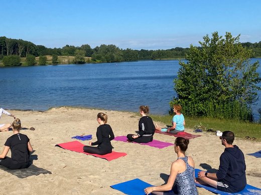 Strand Yoga am Dreiländersee in Gronau Menschen praktizieren Yoga am Strand eines Sees bei klarem Himmel
