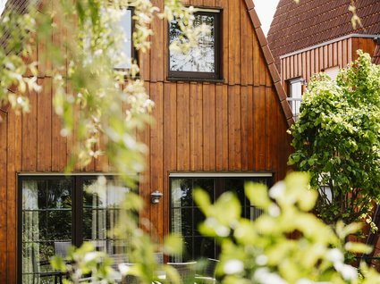 Holidays in an apartment with a lake view Wooden house with large windows and green plants in the foreground
