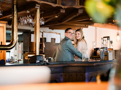 News vom Hotel direkt am See in NRW Paar umarmt sich an der Bar in rustikalem Innenraum