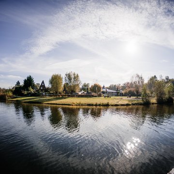 Jobs im Hotel Restaurant Seeblick in Gronau Insel mit Bäumen und Häusern am ruhigen See unter blauem Himmel
