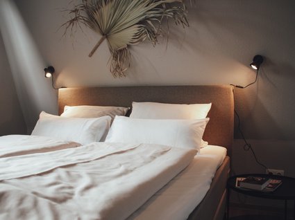 Seeblick: Ferienwohnungen Gronau Gemütliches Doppelbett mit weißen Kissen und Decken in modernem Schlafzimmer