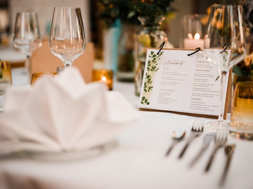 Restaurant Gronau: Seeblick Sfeervol gedekte tafel met wijnglazen, een servet en een menukaart tijdens een evenement.