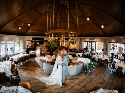 News vom Hotel direkt am See in NRW Brautpaar küsst sich in einem dekorierten Restaurant mit Holzdach