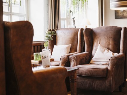 Holidays in an apartment with a lake view Cozy brown armchairs with white pillows in a bright room with windows