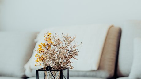 Appartementhotel Seeblick: Bildergalerie Trockenblumen in Glasvase auf rundem Holztisch vor Sofa und Spiegel