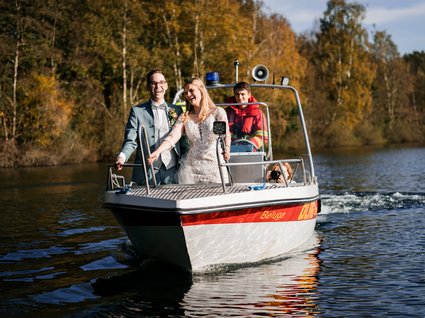 News vom Hotel direkt am See in NRW Lachendes Brautpaar auf Boot mit Rettungsschwimmer und Fotograf auf See
