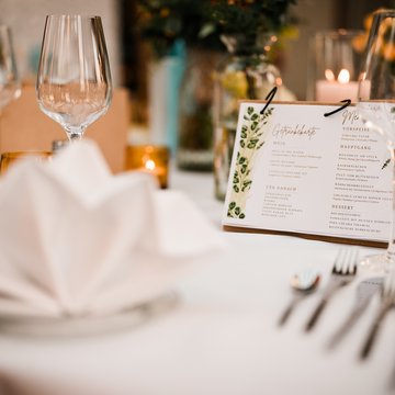Jobs im Hotel Restaurant Seeblick in Gronau Elegantes gedecktes Tisch mit Gläsern, Serviette und Menükarte bei Veranstaltung