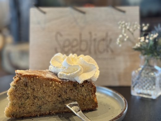 Die kulinarische Fahrradtour durchs Münsterland Ein Stück Kuchen mit Sahne auf einem Teller mit Blick auf ein Holzschild mit Schrift
