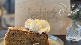 Seeblick: holidays by the lake in North Rhine-Westphalia A slice of cake with whipped cream on a plate in front of a wooden sign with writing