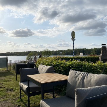 Jobs im Hotel Restaurant Seeblick in Gronau Gemütliche Sitzgruppe am Seeufer mit Wolkenhimmel im Hintergrund