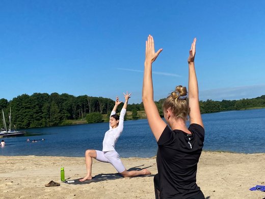 Strand Yoga am Dreiländersee in Gronau Menschen machen Yoga am Strand mit Blick auf das Wasser und blauen Himmel