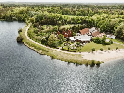 Hotel Seeblick in Gronau Luftaufnahme eines Sees mit Wald und Gebäuden an einem Ufer