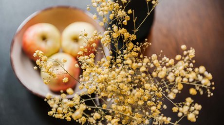 Appartementhotel Seeblick: Bildergalerie Schale mit Äpfeln und gelbe Trockenblumen im Vordergrund