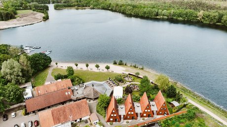 Appartementhotel Seeblick: Bildergalerie Luftaufnahme von spitzen Holzhäusern am Seeufer mit grünen Bäumen und Booten