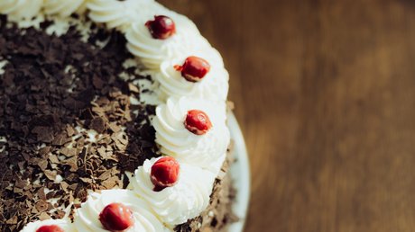 Appartementhotel Seeblick: Bildergalerie Chocoladetaart met slagroom en rode bessen op een houten tafel