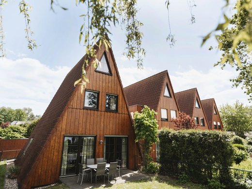 Erholung, Abenteuer und Badespaß für die ganze Familie – direkt am Dreiländersee Reihe von dreieckigen Holzhäusern mit Terrasse und Garten bei sonnigem Wetter