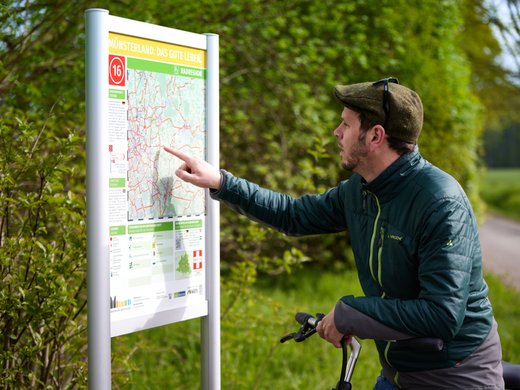 Ihr perfektes Fahrradhotel im Münsterland Mann mit Fahrrad liest eine Radwegkarte im Münsterland
