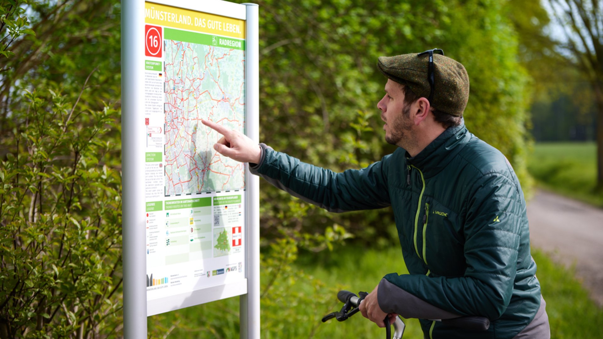 Ihr perfektes Fahrradhotel im Münsterland Mann mit Fahrrad liest eine Radwegkarte im Münsterland