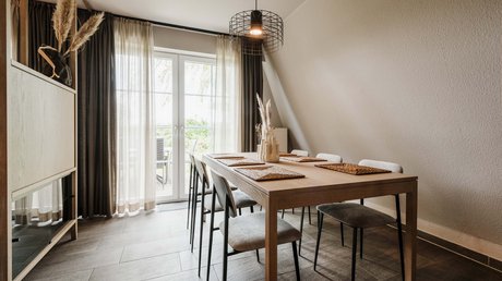 Appartementhotel Seeblick: Bildergalerie Moderner Essbereich mit Holztisch, sechs Stühlen und großem Fenster mit Vorhängen