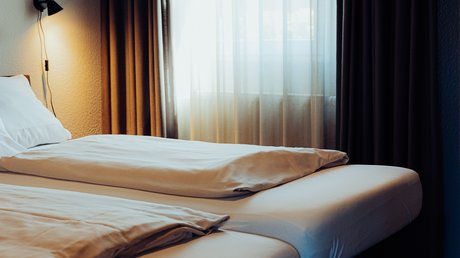 Appartementhotel Seeblick: Bildergalerie Slaapkamer met twee bedden, wit beddengoed en een groot raam met gordijnen