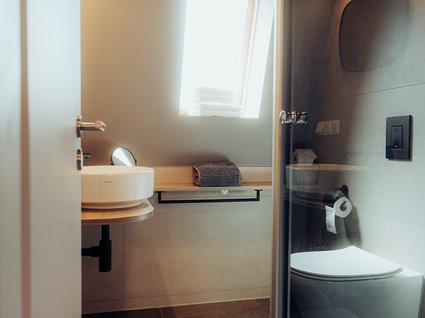 Aparthotel am See in Gronau Modernes Badezimmer mit Waschbecken, Toilette, Spiegel und Fenster
