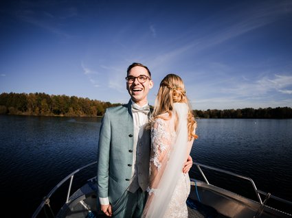 News vom Hotel direkt am See in NRW Glückliches Brautpaar auf einem Boot auf dem See bei klarem Himmel