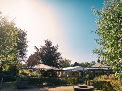 Holidays in an apartment with a lake view Sunny garden with pavilions, bushes, and trees on a clear day