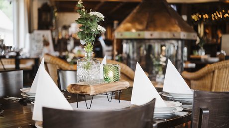 Appartementhotel Seeblick: Bildergalerie Gedekte restauranttafel met witte servetten, bloemen en een open haard op de achtergrond