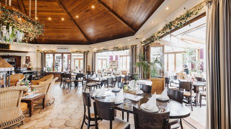 Appartementhotel Seeblick: Bildergalerie Lichte restaurantzaal met gedekte tafels, houten plafond en planten