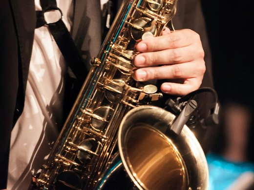 Seeblick: Urlaub am See in NRW Mann spielt Saxophon in formeller Kleidung auf einer Bühne