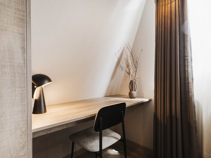 Seeblick: Ferienwohnungen Gronau Minimalistischer Arbeitsplatz mit Holzschreibtisch, Stuhl, Lampe und Vase